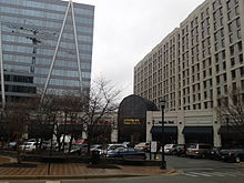 Photo of large city buildings with cars parked on street in front of them