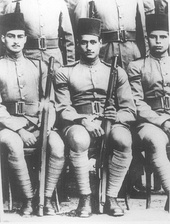 Two seated men in military uniform and wearing fez hats