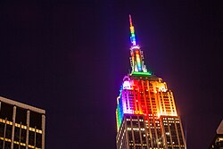 The Empire State Building displays the colors of the Rainbow Flag as an LGBT icon, top. The annual NYC Pride March in June (seen here in 2018) is the world's largest LGBT event, imaged below.[273][274]
