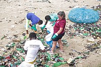 A man and woman dragging a bag of plastic waste collected from the beach in Ghana