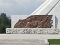 Bronze relief at base showing the Korean people