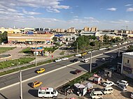 View of the central market area of Urgench from the fifth floor of the Hamkor Bank building. In the background, the blue and white building of the "Gipermarket", the largest shopping centre in Urgench.