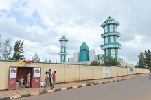 Photograph of the mosque from the street, with a small local shop visible in the foreground