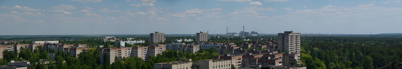  A panorama of Pripyat during summer. The Chernobyl power plant, currently undergoing decommissioning, is visible in the distance, at top center.