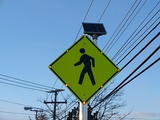 A pedestrian crossing sign in the United States with solar-powered lit outline.