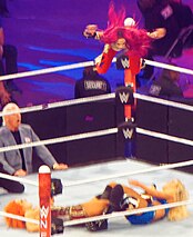 Sasha Banks (top) performing the frog splash to Charlotte Flair (with Ric Flair)  and Becky Lynch (left) at Wrestlemania 32