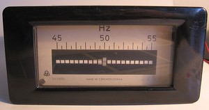 A resonant-reed frequency meter, an obsolete device used from about 1900 to the 1940s for measuring the frequency of alternating current.  It consists of a strip of metal with reeds of graduated lengths, vibrated by an electromagnet.  When the unknown frequency is applied to the electromagnet, the reed which is resonant at that frequency will vibrate with large amplitude, visible next to the scale.