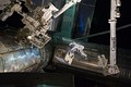 Mike Fossum rides on the ISS's robotic arm as he transfers the RRM to the SPDM for temporary storage