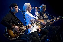 Pickler singing with guitarists on either side of her