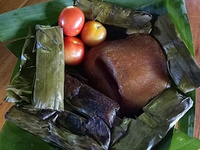 Chicharon Camiling with freshly picked tomatoes surrounded by Tupig, and Pinais, native delicacies.