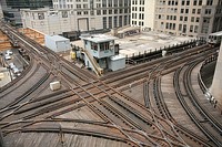 Left: Railway turnouts; Right: Chicago Transit Authority control box guides elevated Chicago 'L' north and southbound Purple and Brown lines intersecting with east and westbound Pink and Green lines and the looping Orange line above the Wells and Lake street intersection in the loop at an elevated right of way.