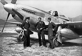 Three men in dark military clothing standing before a P-51 Mustang single-engined fighter plane