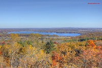 Flat landscape with lake in background and fall-colored orange and yellow trees