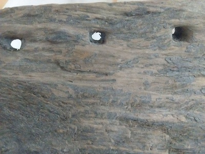 Detalle de los agujeros en el borde de un fragmento de tablón conservado en el museo de Achao.
