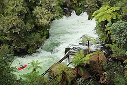 Kayaker at Okere Falls, with the remains of the powerhouse visible in the lower right