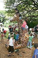 Children playing on a giraffe statue at the zoo
