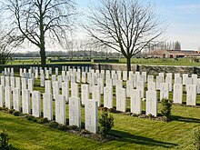 Rows of white gravestones in a field.