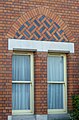 A brickwork pattern above the ground floor windows created using alternating red and blue bricks.