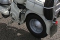 The image shows the port side (left side when facing forward) of a Lambretta Model C. The wheel and the lug nut are visible but there is no visible connection between the wheel and the rest of the scooter.