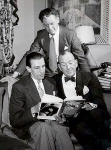 three middle-aged men looking at a book
