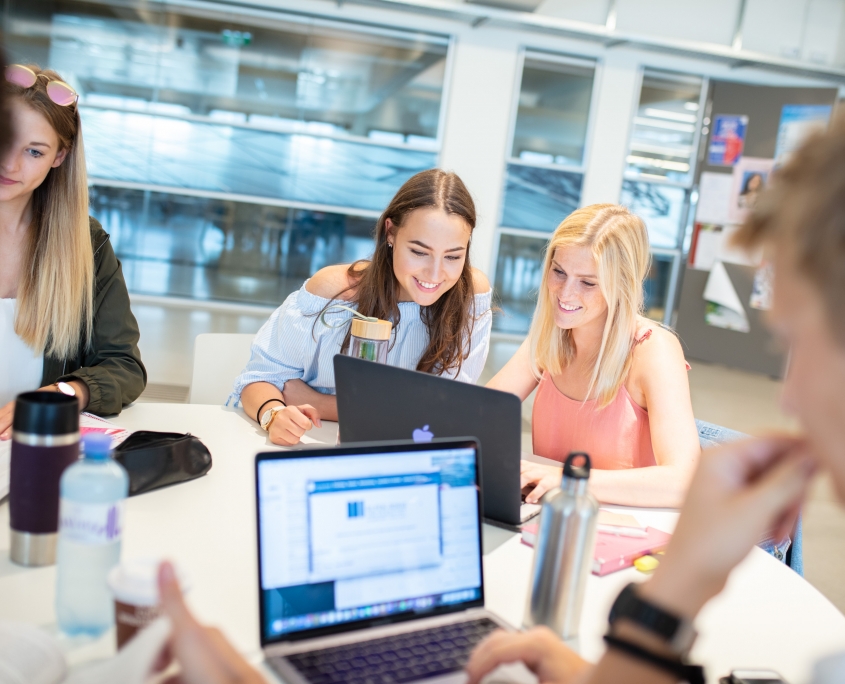 Studierende vor einem Laptop in der Aula