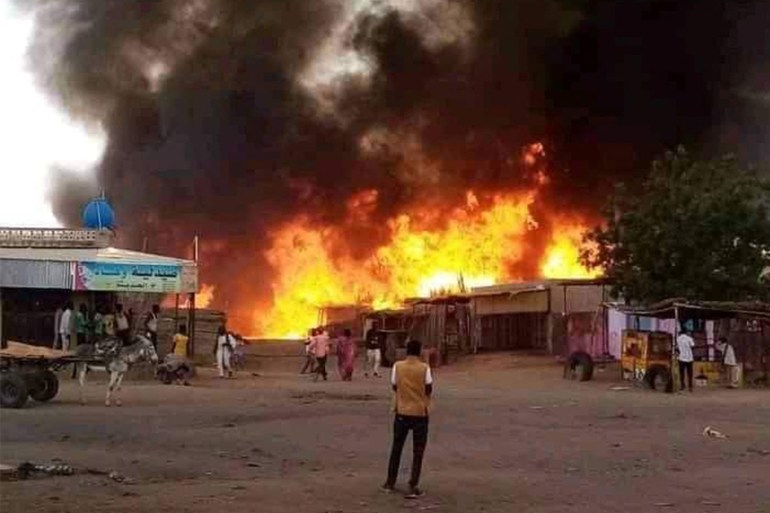 A man stands by as a fire rages in a livestock market area in al-Fasher, the capital of Sudan's North Darfur state
