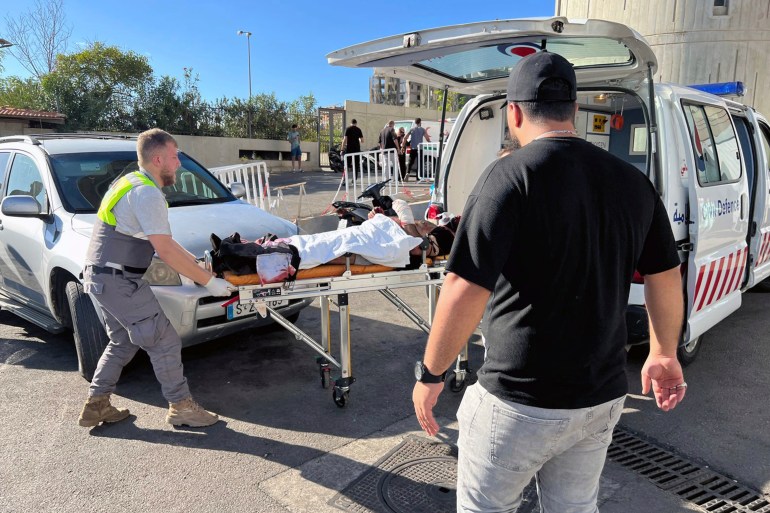 Civil Defense first-responders carry a wounded man whose handheld pager exploded at al-Zahraa hospital in Beirut