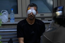 A man who was injured by the explosion of a handheld device triggered by Israel sits outside the Eye Specialist hospital in Beirut, Lebanon [Hussein Malla/AP]