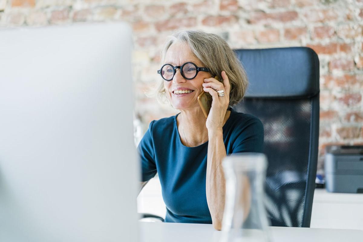 Senior businesswoman at her desk using cell phone