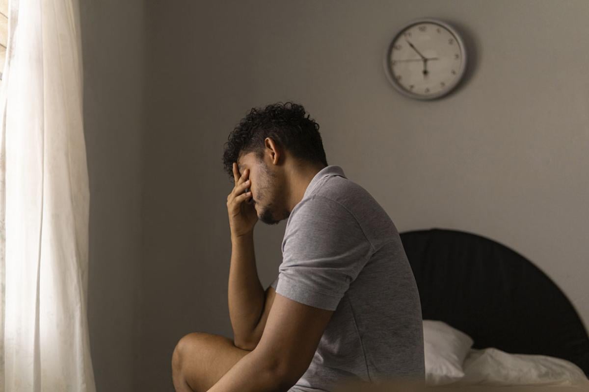 Tired person sits on a bed