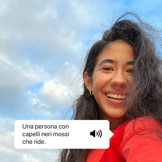 VoiceOver che descrive una foto e mostra il testo pronunciato, Una persona con capelli neri mossi che ride