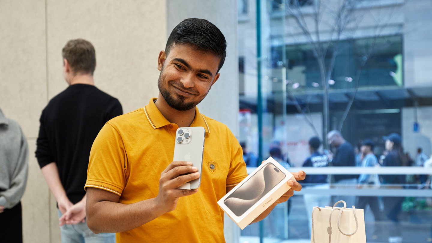 Una persona sonriente sujeta su nuevo iPhone 15 Pro dentro de Apple Sydney, Australia.