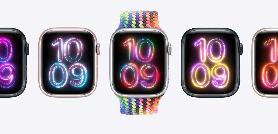 Apple Watch Series 9-ure med en ny Flettet Solo Loop i Pride Edition i mange neonfarver på det midterste ur og urskiven Pride-udstråling vist i forskellige farver på hvert ur.