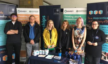 A mixed group of University of Oxford Apprentices at a careers fair talking about Oxfordshire Apprenticeships