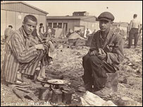 Two survivors prepare food outside the barracks. 
