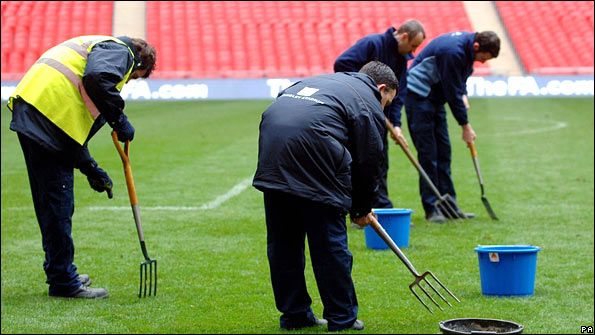 Groundsmen work on Wembley pitch