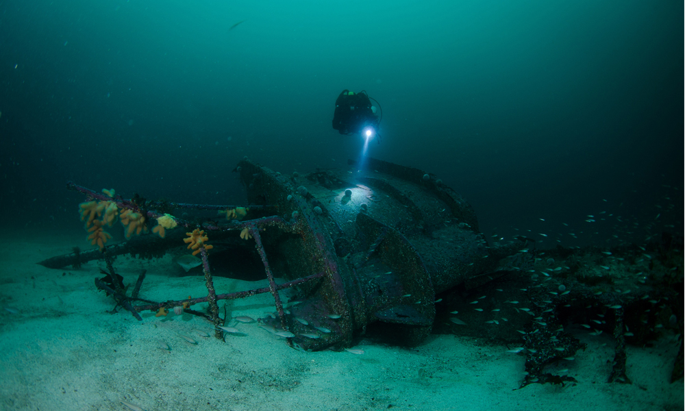 Diver with torch approaching wreck in Shetland