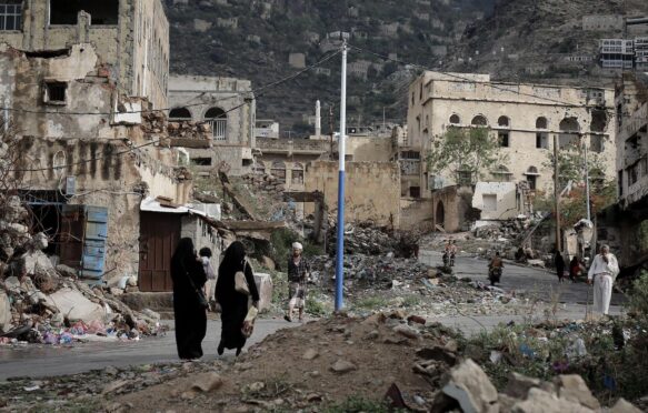 People walk on the rubble of houses destroyed by war in Taiz, Yemen.