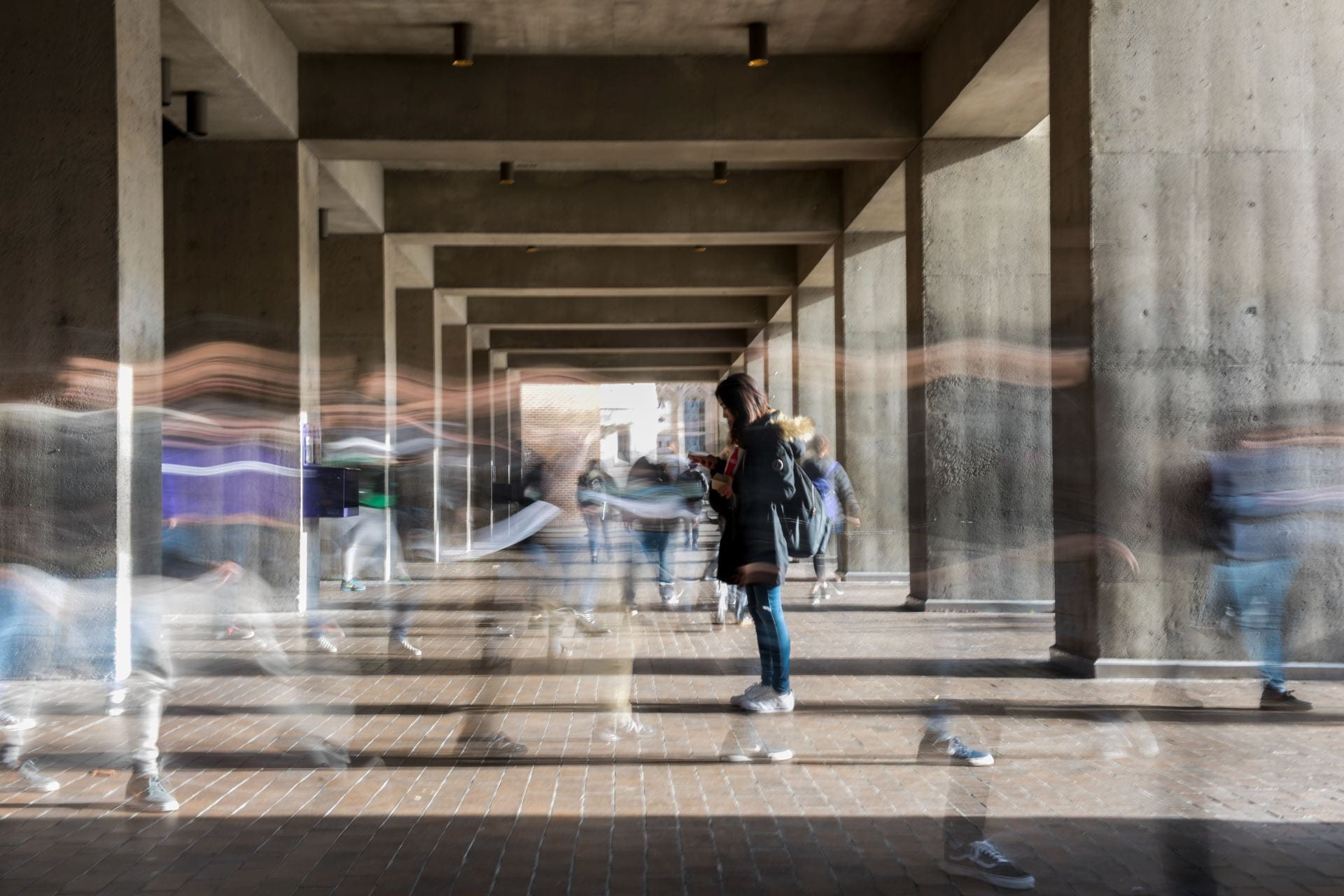 Blurred people walking in an outdoor passageway.