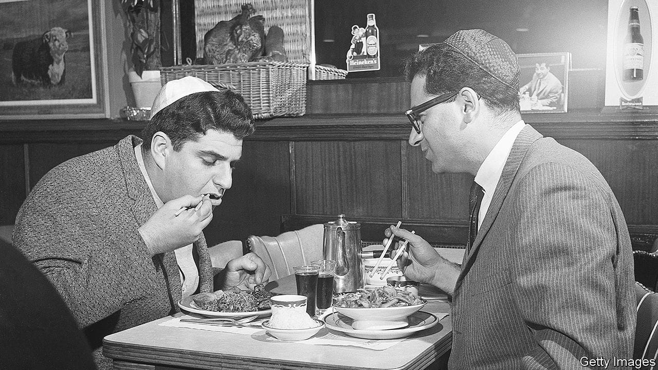 Two men enjoy Chinese cuisine prepared by Chinese chefs within the guidelines of kosher food preparation at a restaurant.