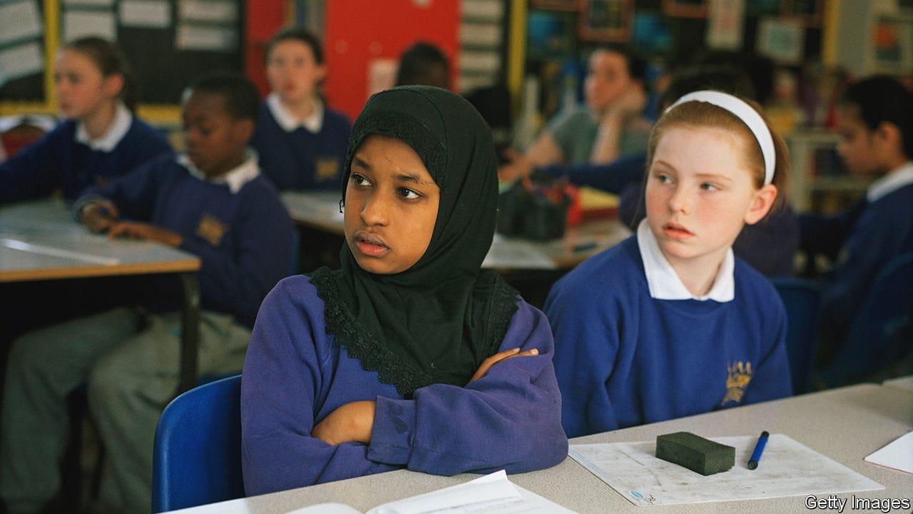 A Muslim child from Bangladesh sits next to a Catholic child from Ireland at Kingsmead Primary School, which primarily serves children who live on the Kingsmead Estate in Homerton, Hackney, close to the site of the 2012 Olympic Games. Its population is diverse, a fact reflected in the 42 different languages spoken by the children as well as the composition of the pupils, 95% of whom are from an ethnic minority. The largest ethnic group is African, followed by Afro Caribbean, Bangladeshi, Turkish, Eastern European, and Irish traveller. Kingsmead children are, according to government data, some of the most economically deprived in the country. Despite these challenges the school strives to achieve the highest standards, with academic achievement above the national average ? impressive, considering that 85% of pupils speak English as a second language. (Photo by Gideon Mendel/In Pictures/Corbis via Getty Images)