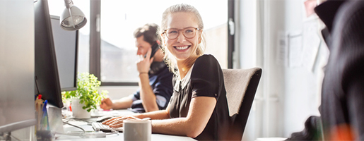 On this picture you can see two employees at thier computer, one of them is smiling