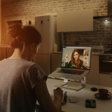 Female teleworker taking notes during video conference on her laptop