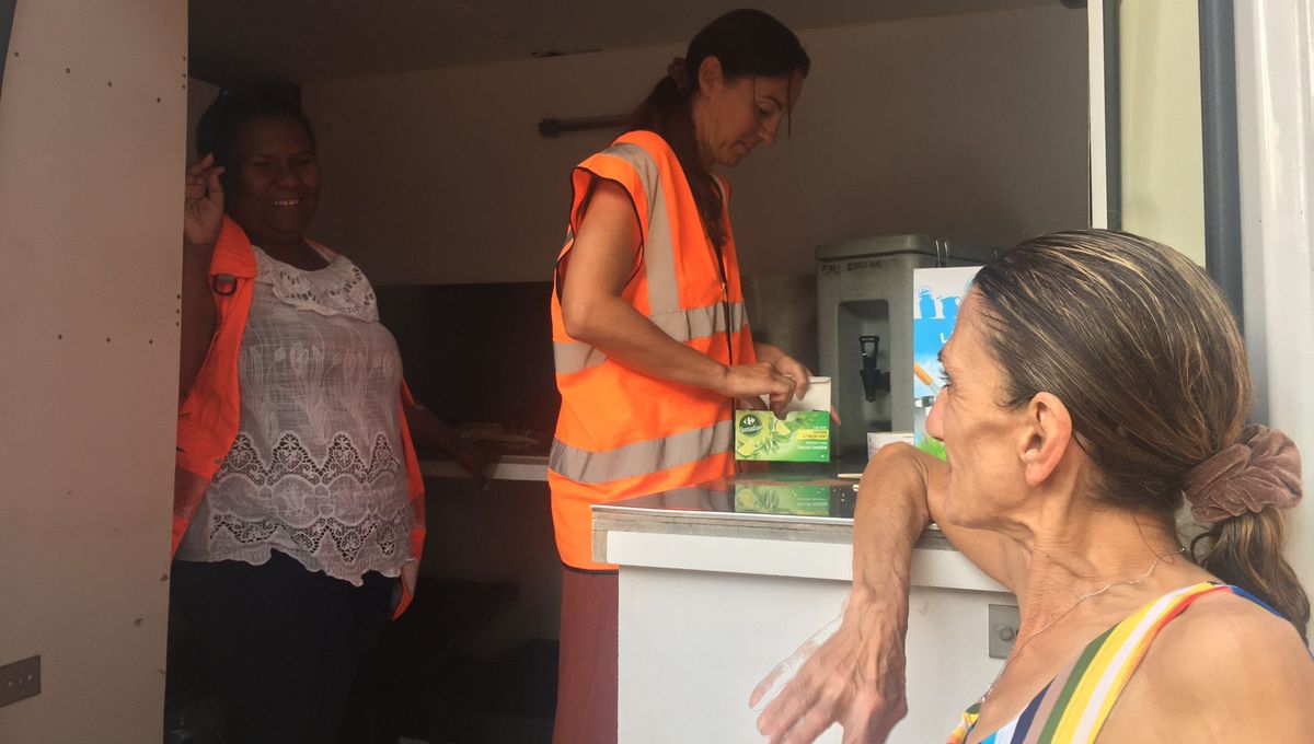 Une bénéficiaire de la Croix-Rouge attend devant le camion que les bénévoles lui distribue un repas.