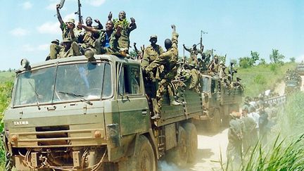 Photographie d'archive prise le 19 mai 2003 : le dernier groupe de soldats des Forces de défense du peuple ougandais (UPDF) revient par la ville de Goli après s'être retiré de l'Ituri assiégée par la République démocratique du Congo (RDC). (PETER BUSOMOKE / AFP)