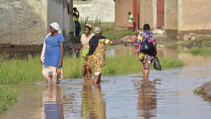 Des femmes marchent dans l'eau, au nord-ouest de Bujumbura, au Burundi, après des pluies torrentielles qui ont détruit une centaine de maisons en mars 2017.&nbsp;&nbsp; (STRINGER / AFP)