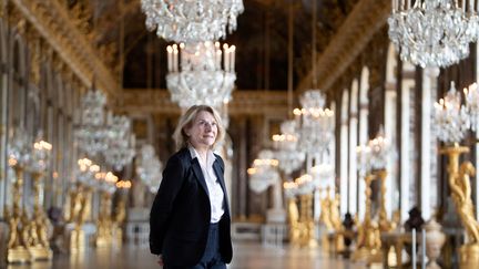 Catherine Pegard, présidente de l'établissement public du château, du musée et du domaine de Versailles, pose dans la Galerie des Glaces du château de Versailles, près de Paris, le 17 mai 2021. (MARTIN BUREAU / AFP)