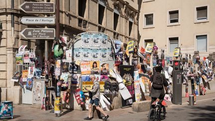 Des passants devant une grille pleine d'affiches pendant la grande parade d'ouverture du Festival Off d'Avignon, le 2 juillet 2024. (LUCIA TROUILLER / HANS LUCAS / AFP)