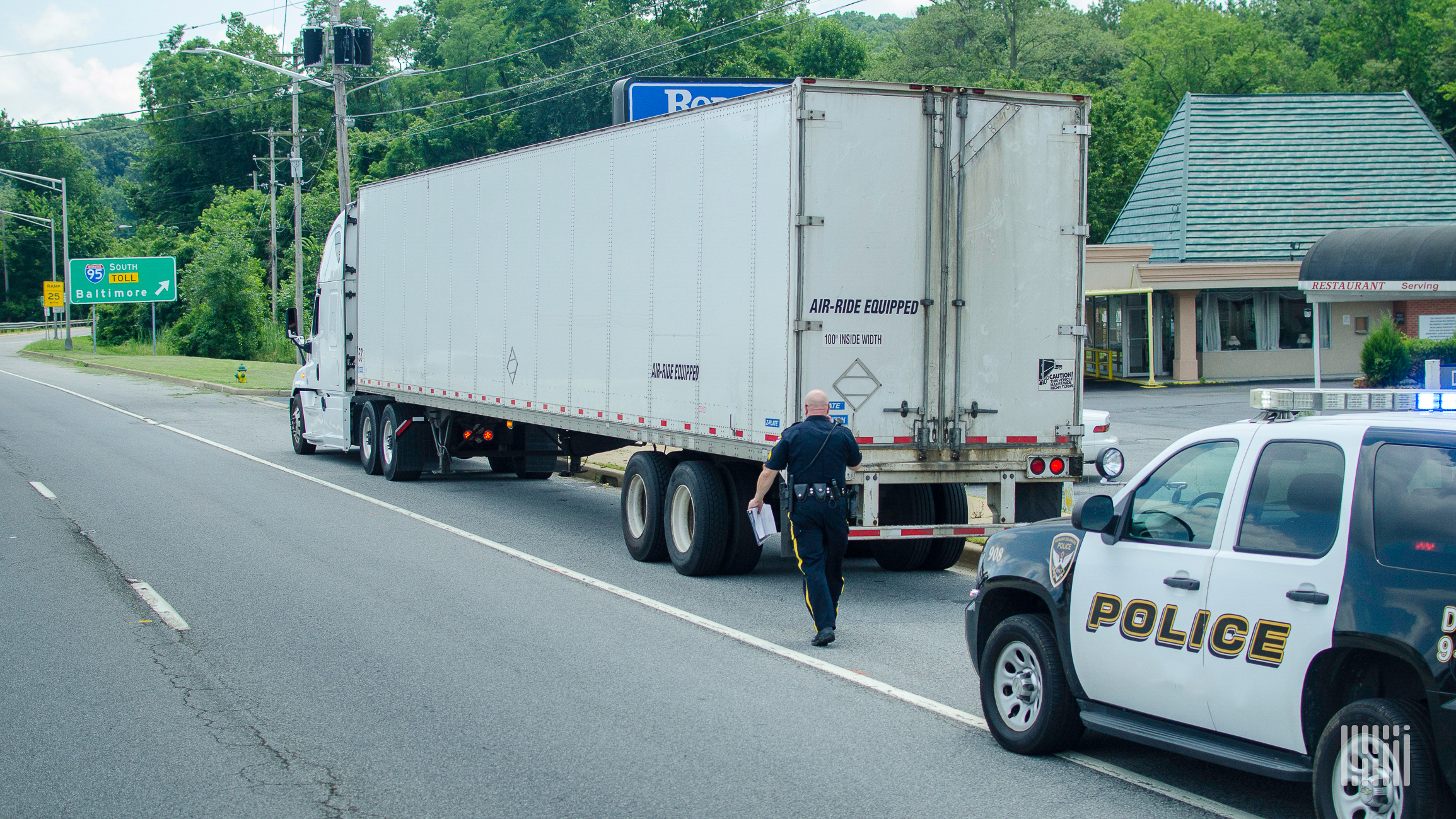 Police officer walks up to tractor trailer truck