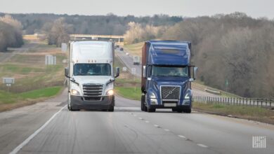 Freightliner and Volvo trucks side by side on highway
